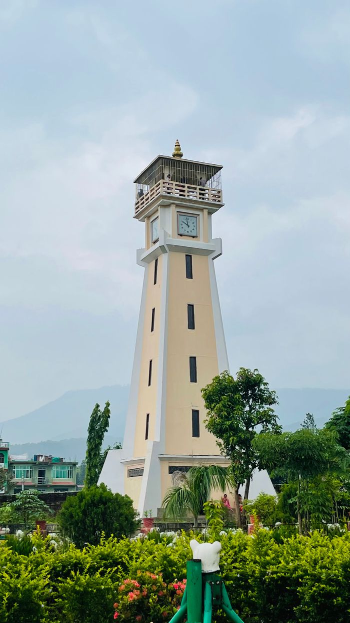 Charming clock tower surrounded by lush greenery in a peaceful urban park, ideal for travel enthusiasts.