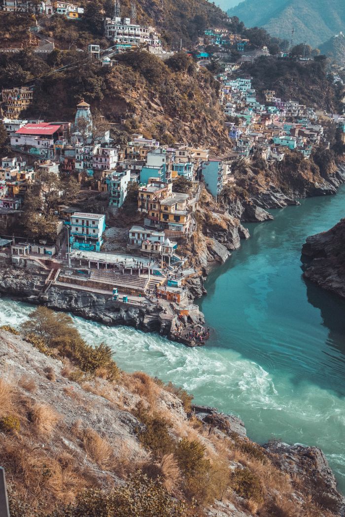 Picturesque view of Rishikesh, India with colorful buildings perched on rocky hills by the Ganges River.